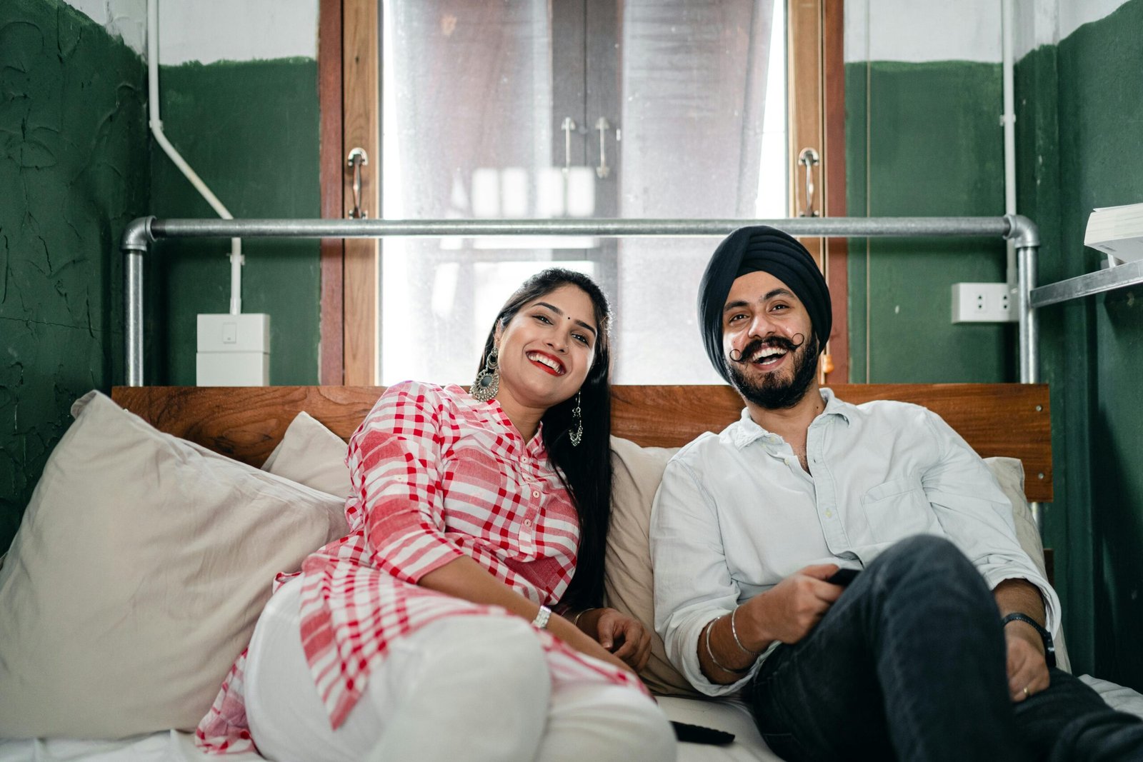 A joyful couple relaxing on a bed indoors, enjoying leisure time together.